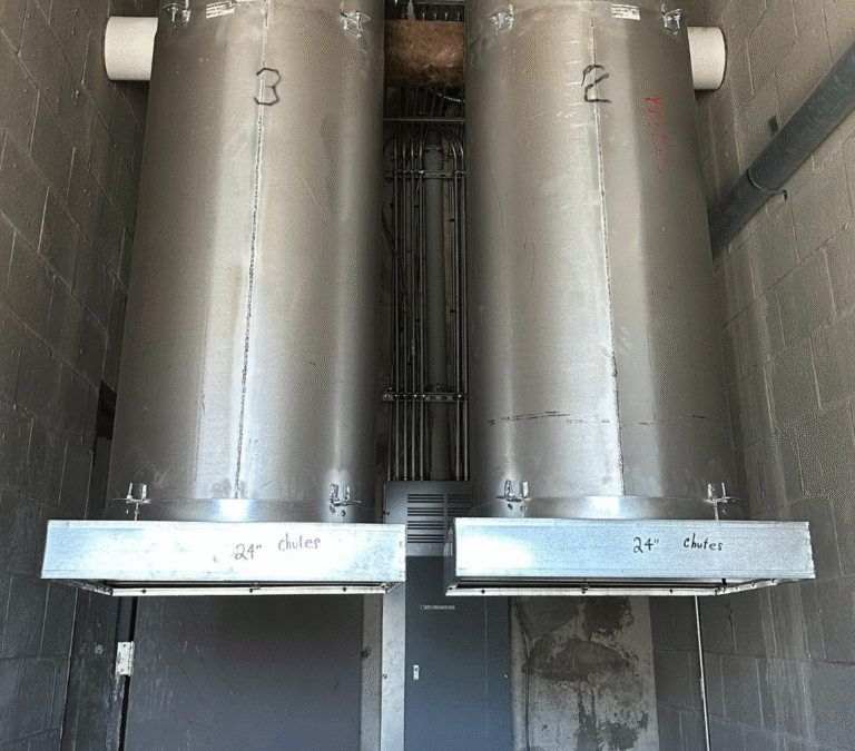 Dual 24-inch commercial trash chutes installed in a multi-story utility shaft with vertical conduit alignment