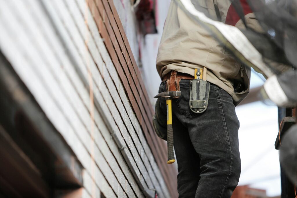 Construction worker wearing a tool belt with hammer and knife at a job site.