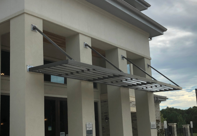 Commercial building entrance with aluminum sunshade awnings installed above doorways