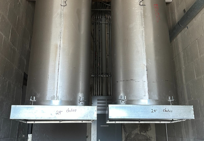 Dual 24-inch commercial trash chutes installed in a multi-story utility shaft with vertical conduit alignment
